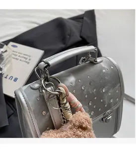 Detail of silver rhinestone handbag with pink plush bear charm and sturdy handle