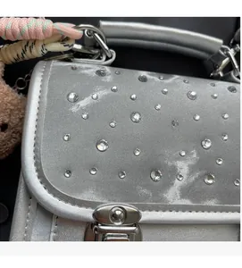 Close-up of shiny silver glitter backpack with rhinestone embellishments and woven strap detail