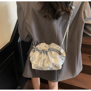 Close-up of a silver pleated cloud bag with shimmering rhinestones and metal chain