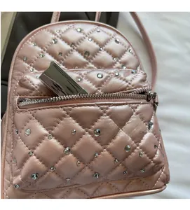 Close-up of pink quilted mini backpack with rhinestone decor and lipstick in front pocket