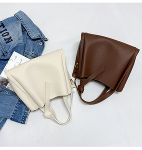 Detail of lychee pattern leather texture on minimalist bucket bags in beige and brown
