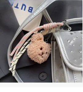 Pink plush bear charm with silver metal chain on a rhinestone embellished backpack