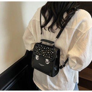 Close-up of black mini backpack with silver rivets and branded lettering on leather