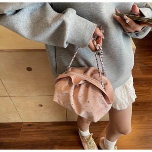 Detailed close-up of pink pleated cloud bag with rhinestones and metal chain strap