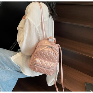 Detail of pink quilted mini backpack with rhinestones on a model in a casual setting
