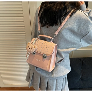 Detail of pink faux leather backpack with rhinestones and a brown teddy bear charm