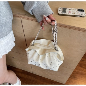 Detail of white pleated cloud bag featuring silver rhinestone studs and a metal chain strap