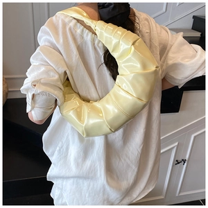 Détail du sac croissant jaune clair avec texture plissée et finition en cuir brillant