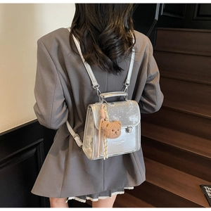 Silver mini backpack with sequined flap and cute brown plush bear charm on wooden stairs
