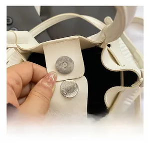 Détail du fermoir magnétique argenté et cuir grainé sur un sac à main blanc