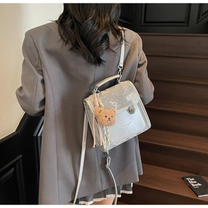 Silver-grey leather crossbody bag with metal buckle and plush bear charm detail