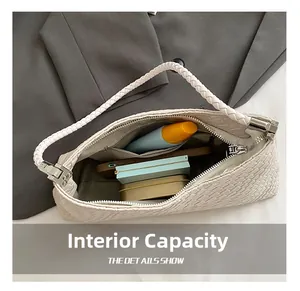 Interior capacity detail of woven white underarm bag showing cosmetics and smartphone