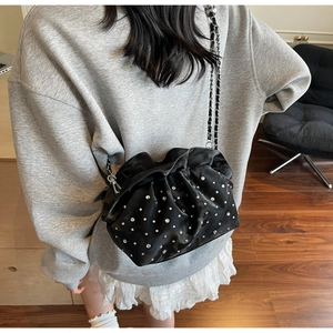 Detail of black rhinestone pleated cloud bag with elegant chain strap on shoulder