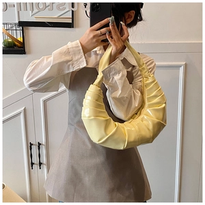 Détail du sac croissant jaune brillant avec texture plissée et finition miroir éclatante
