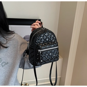 Detailed close-up of mini quilted backpack with silver rhinestone studs and leather straps