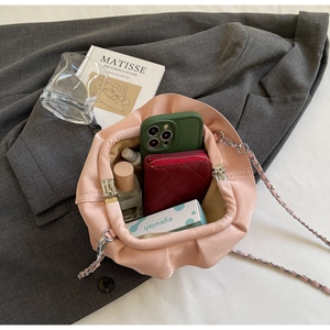 Interior storage of pink pleated dumpling bag showing phone, wallet and perfume capacity