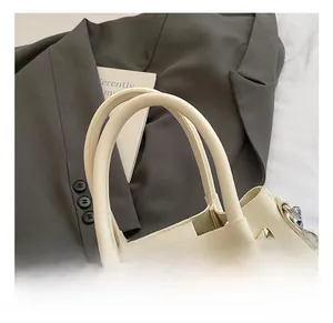 Détail de la couture en cuir tressé et de la boucle en métal sur ce sac fourre-tout crème