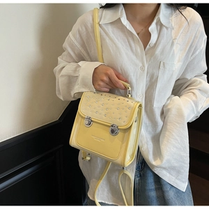 Detail of yellow leather crossbody bag with sparkling silver rhinestones and dual buckles