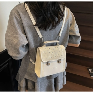 Detail of off-white PU leather backpack with shimmering rhinestones on dark wooden stairs