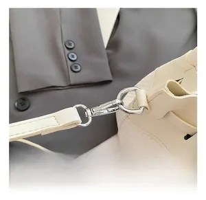 Détail du crochet en métal argenté et de la bandoulière amovible du sac crème