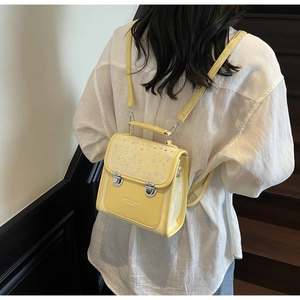 Detail view of mini yellow leather backpack featuring sparkling silver rhinestone flap