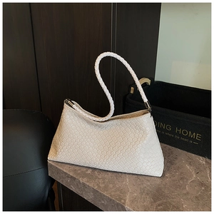 Detail of white woven leather underarm bag with artisan cross-weave on marble surface