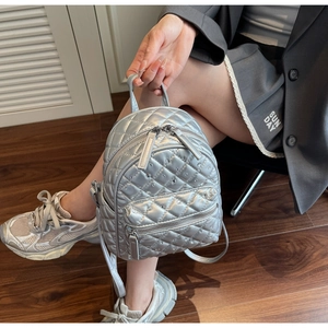 Close-up of silver mini backpack featuring quilted stitching and rhinestone embellishments