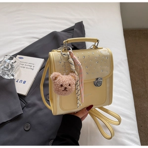 Detail of light yellow leather backpack with rhinestones and cute bear pendant charm