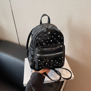 Mini black quilted backpack with sparkly rhinestones on top of a white book