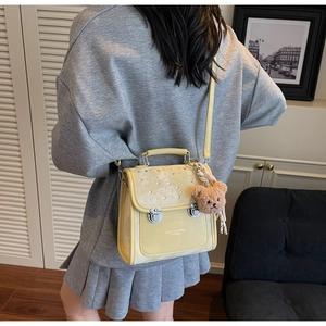 Close-up of a yellow rhinestone crossbody bag featuring a plush bear charm and luxury details