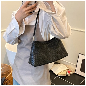 Detailed shot of a black woven leather shoulder bag with a silver metal buckle connector