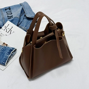 Brown lychee leather tote bag with gold zipper on white linen and denim background