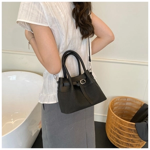 Détail d'un sac à main noir avec rayures verticales et boucle argentée sur un mannequin