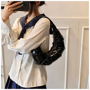 Détail du sac à bandoulière plissé en cuir brillant noir avec fermeture éclair dorée