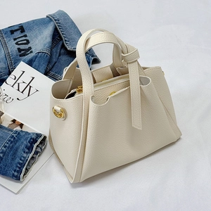 Minimalist beige pebble leather handbag with gold hardware and knotted handle detail