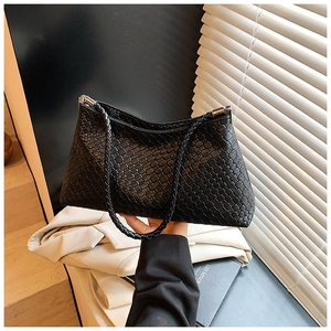 Close-up of black woven texture underarm bag with silver hardware and slim shoulder strap