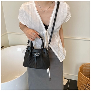 Détail d'un sac cabas noir matelassé avec boucle en cuir et bandoulière amovible