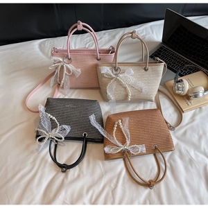 Detail view of woven straw handbags in four colors with pearl and lace bow charms