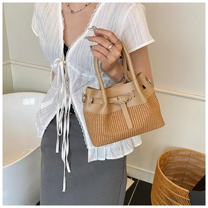 Détail du sac seau en paille bohème avec patchwork de cuir et boucle en métal porté