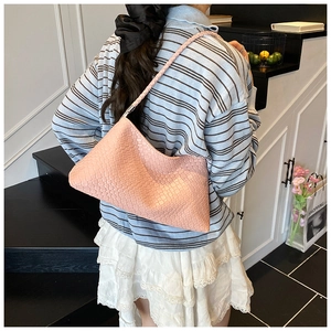 Pink woven underarm hobo bag shown on model with intrecciato pattern in casual style