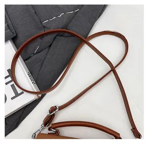 Close-up of adjustable strap and silver metal buckle on a brown leather crossbody bag