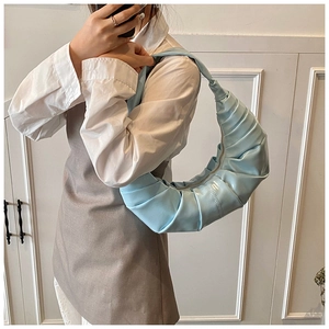 Détail du sac à plis bleu clair avec finition brillante et bandoulière en demi-lune