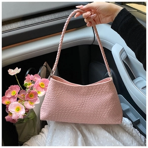 Pink crocodile pattern baguette bag with a stylish woven handle shown in a car interior