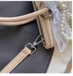 Detail view of the durable silver metal hook connecting the shoulder strap to the straw bag