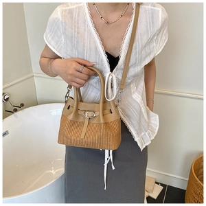 Détail d'un sac bandoulière en cuir et paille porté avec une tenue élégante chic