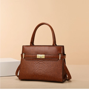 Detail of vintage brown shoulder bag showing crocodile pattern and gold metal lock clasp