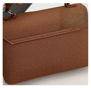 Detail shot of the high-quality brown woven fabric and leather handle of this messenger bag