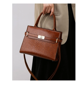 Close-up of vintage brown handbag featuring snake skin texture and gold twist lock clasp