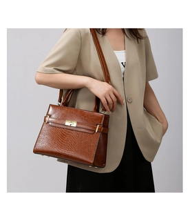 Detail of brown hobo bag with snakeskin texture contrast and gold metal turn-lock buckle