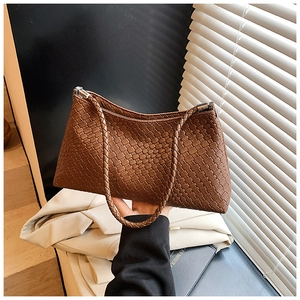 Detailed view of brown woven leather texture on retro shoulder bag with silver hardware
